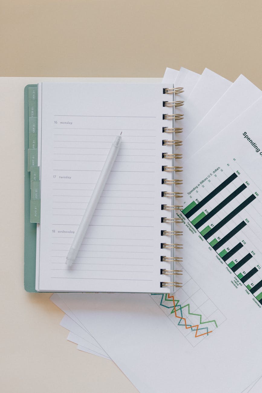 An open planner with a pen next to clear expense charts — visualizing and tracking household spending